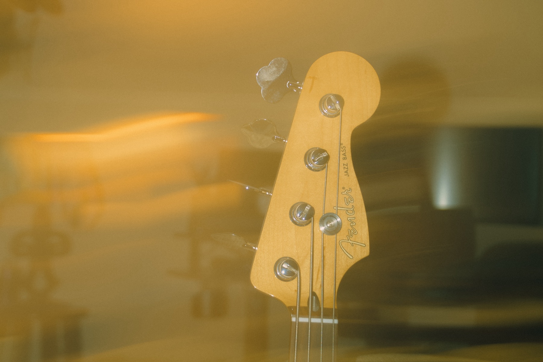 A Fender Jazz Bass headstock in warm studio light