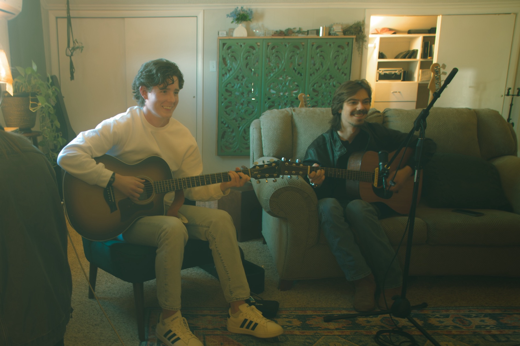 Two artists playing acoustic guitars together in the lounge